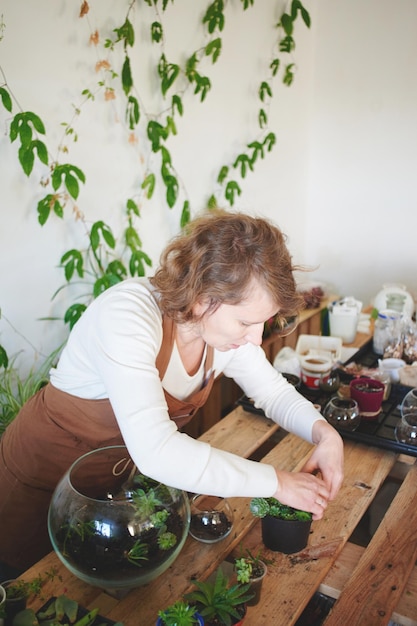 Hobby. Una mujer crea un mini terrario con plantas para el diseño de interiores.