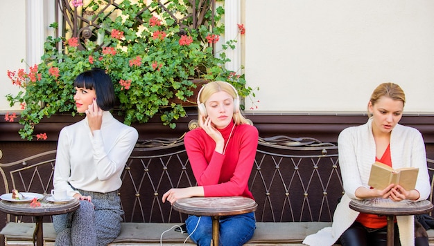 Hobby und Freizeit Unterschiedliche Interessen Gruppe hübscher Frauen Caféterrasse unterhalten sich mit Lesen, Sprechen und Zuhören Informationsquelle Weibliche Freizeit Wochenende entspannen und Freizeit