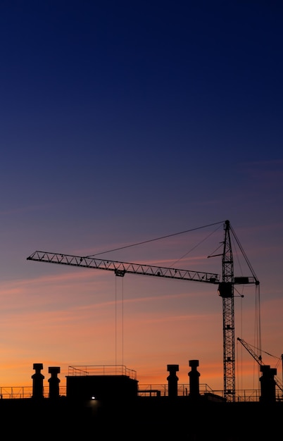 Hochhauskran auf dem Hintergrund des Sonnenunterganghimmels