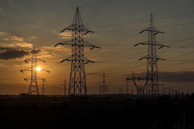 Hochspannung der Stromleitungen bei schönem Sonnenuntergang.