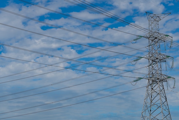 Hochspannungs-Strommast und elektrischer Draht gegen blauen Himmel und Wolken. Unteransicht des elektrischen Pylons. Hochspannungsgitterturm mit Kabel.