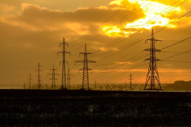 Hochspannungsleitung in einem Feld bei Sonnenuntergang im Winter