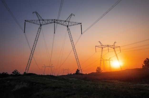 Hochspannungsleitungen bei feurigem Sonnenaufgang