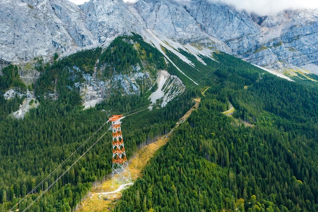 Hochspannungsmast hoch in den Bergen, umgeben von Bäumen