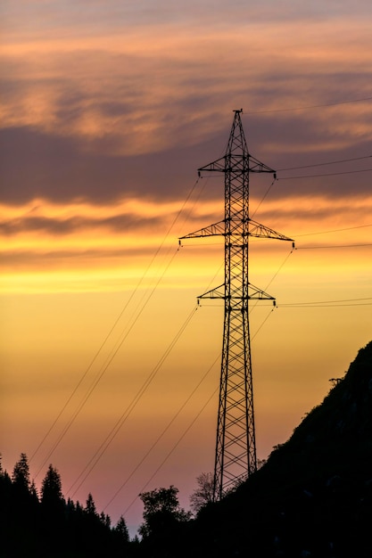 Hochspannungsmast in den Bergen bei Sonnenuntergang Bewölkter Himmel Berghintergrund