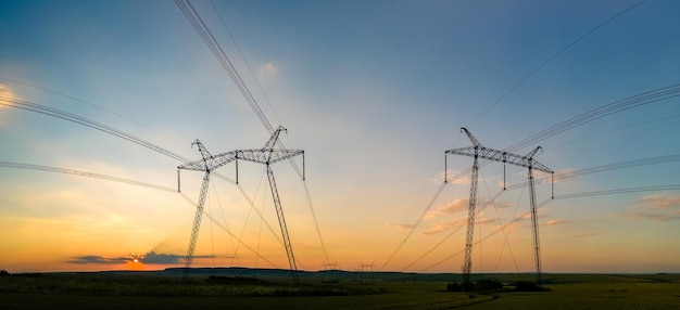 Hochspannungstürme mit Stromleitungen bei Sonnenuntergang