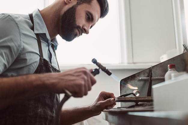 Hochtemperatur-Juwelier, der in seiner Schmuckwerkstatt einen Silberring lötet und schweißt