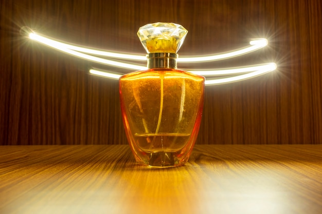 Hochwertige Parfümflasche isoliert auf Holzhintergrund mit Lichtspureffekt
