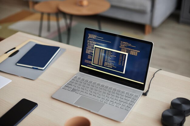 Hochwinkel-Laptop mit Code-Linien am Schreibtisch im Büro