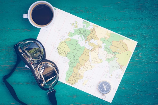 Hochwinkelansicht auf eine Kaffeetasse mit Schnorchel und Navigationskompass auf der Karte über dem Tisch