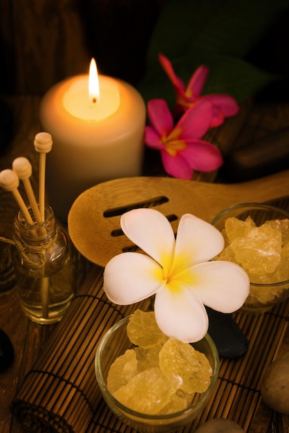 Hochwinkelansicht der Frangipani-Blumen mit Kerze und Felssalz im Spa