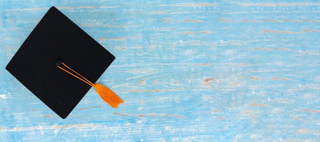 Foto hochwinkelansicht der graduiertenkappe auf blauem holz