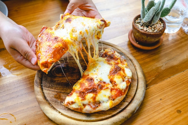 Foto hochwinkelansicht der hand, die pizza auf dem tisch hält