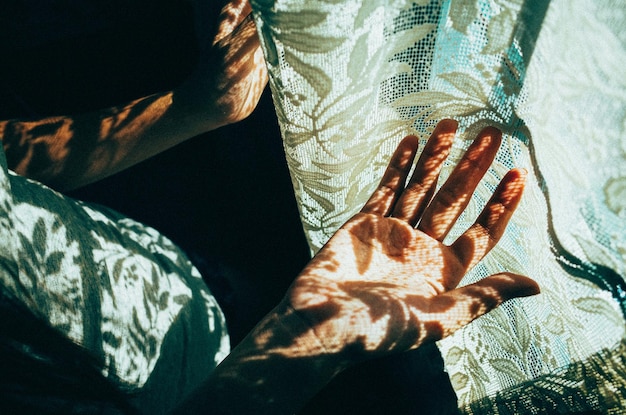 Foto hochwinkelansicht der handfläche einer person durch vorhang mit sonnenlicht