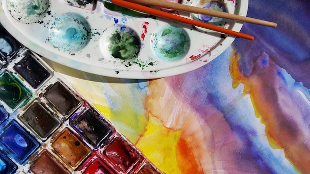 Hochwinkelansicht der Palette auf farbenfrohen Gemälden