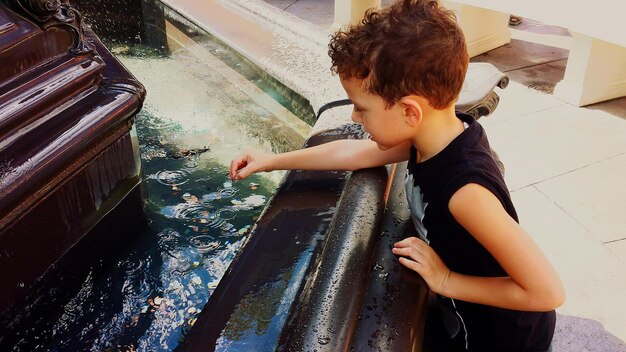 Foto hochwinkelansicht des jungen, der vor dem wunschbrunnen steht