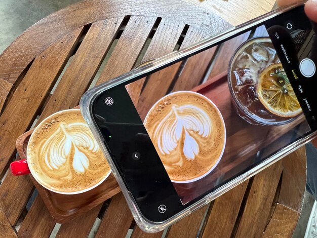 Foto hochwinkelansicht des kaffees auf einem holztisch über die kamera des telefons