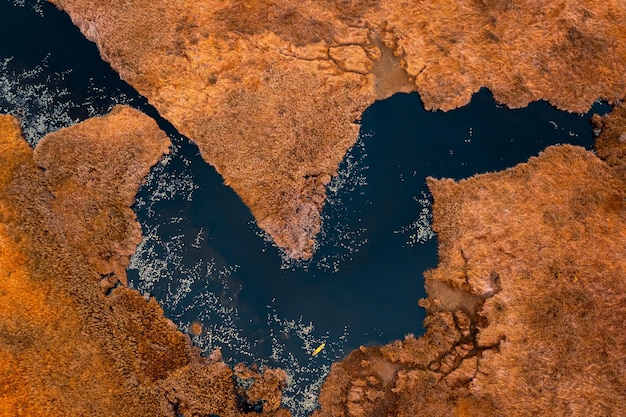 Hochwinkelansicht des kleinen touristischen Kajakfahrens im schwarzen See und der trockenen Orangenwiese