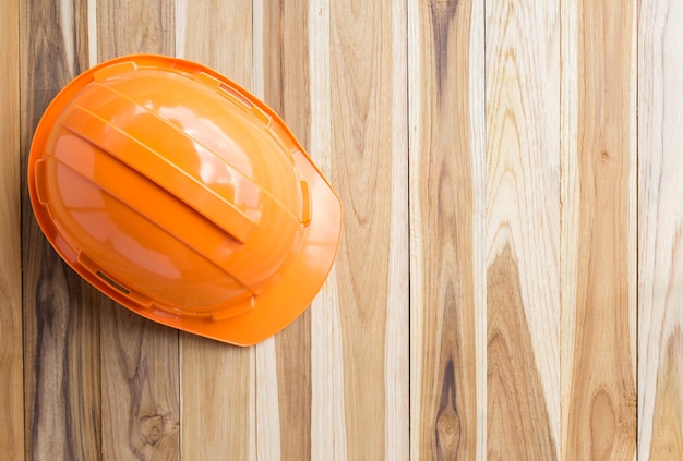 Hochwinkelansicht des orangefarbenen Sicherheitshelms auf dem Hintergrund eines Holztisches mit Kopierplatz