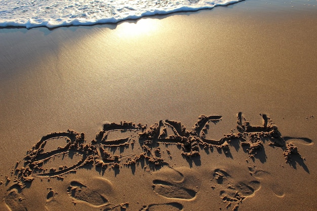 Hochwinkelansicht des Textes am Sandstrand beim Sonnenuntergang