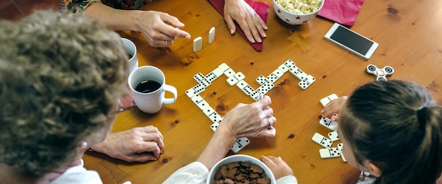 Foto hochwinkelansicht einer familie, die beim essen am tisch domino spielt