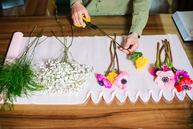 Foto hochwinkelansicht einer frau, die einen blumenstrauß auf dem tisch hält