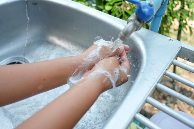 Hochwinkelansicht einer Frau, die sich die Hände mit Seife und warmem Wasser wäscht