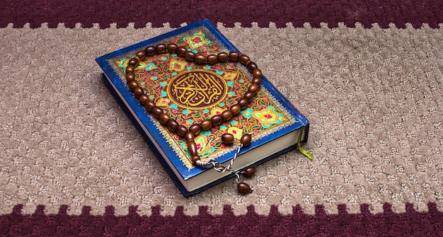 Hochwinkelansicht einer Perlenkette mit Koran auf einem Teppich