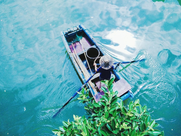 Foto hochwinkelansicht einer person, die ein boot im see rudert