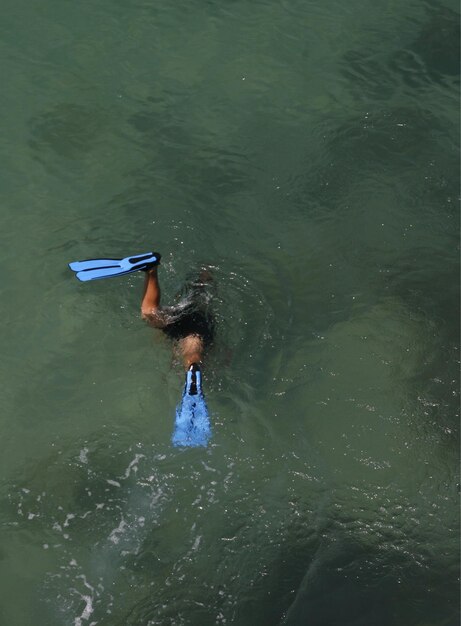 Foto hochwinkelansicht einer person mit flossen, die ins meer taucht