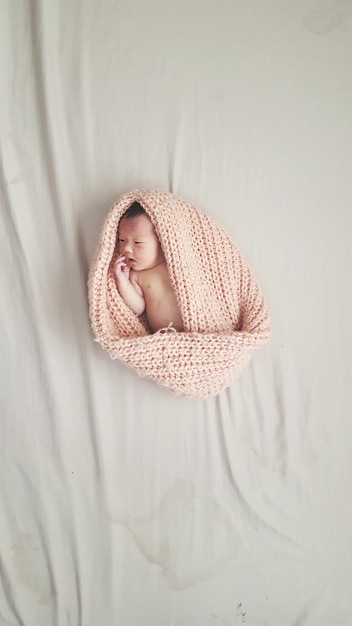 Hochwinkelansicht eines Babys, das zu Hause auf dem Bett liegt