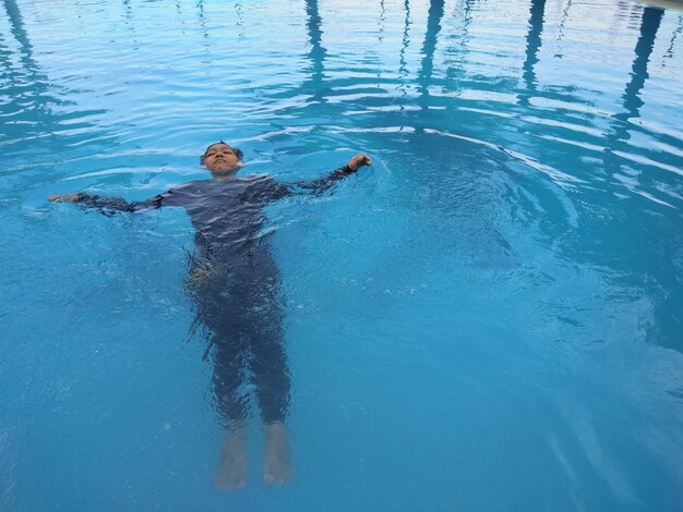 Foto hochwinkelansicht eines jungen, der im pool schwimmt