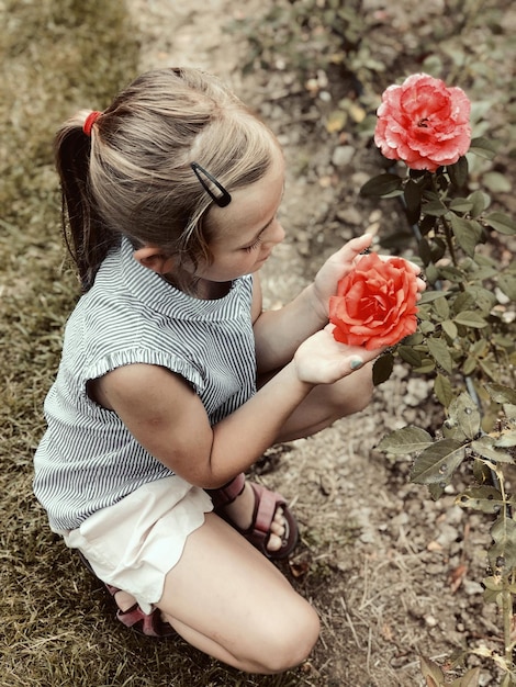 Foto hochwinkelansicht eines mädchens, das eine rosenblume auf einer pflanze hält