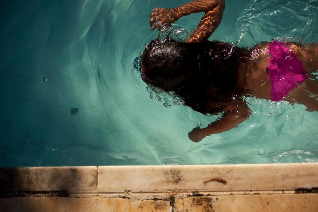 Foto hochwinkelansicht eines mädchens, das im pool schwimmt