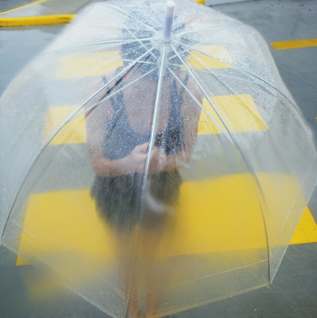 Foto hochwinkelansicht eines mädchens mit regenschirm, das während der regenzeit auf der straße geht