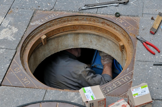 Hochwinkelansicht eines Mannes in einem Schlauchloch auf der Straße