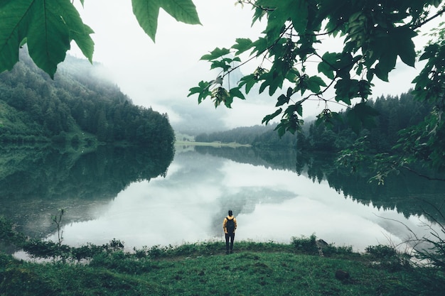 Foto hochwinkelansicht eines mannes mit rucksack, der bei nebligem wetter am see steht