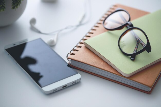 Foto hochwinkelansicht eines smartphones mit büchern und brillen auf dem tisch