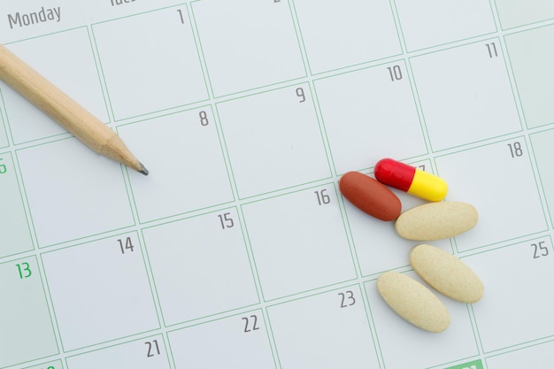 Hochwinkelansicht von Arzneimitteln mit Bleistift auf Kalender