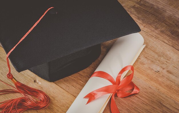 Hochwinkelansicht von Diplom- und Abschlusshut auf einem Holztisch