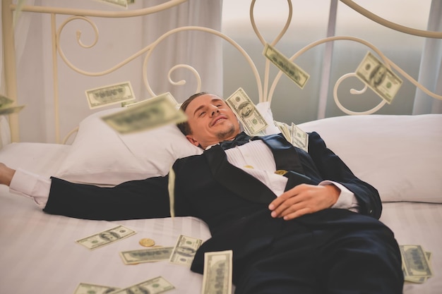 Hochwinkelansicht von einem mittleren erwachsenen Mann mit Geld, der zu Hause auf dem Bett liegt