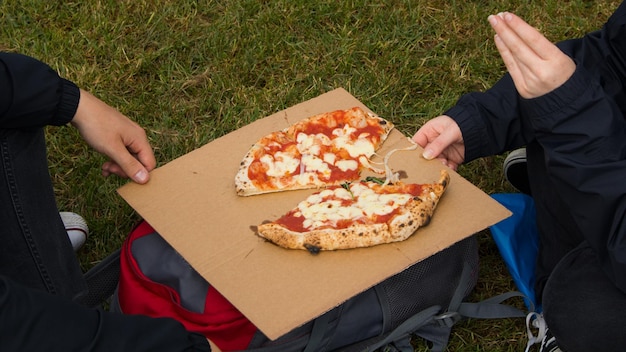 Foto hochwinkelansicht von einer hand, die eine pizza auf dem feld hält