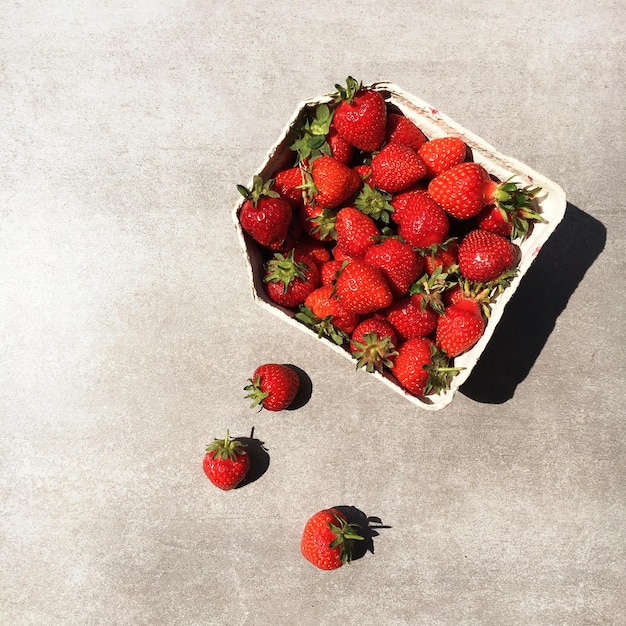 Hochwinkelansicht von Erdbeeren in einem Behälter auf dem Boden