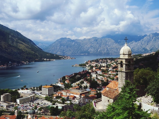 Hochwinkelansicht von Gebäuden am Fluss gegen Berge und bewölkten Himmel in Kotor