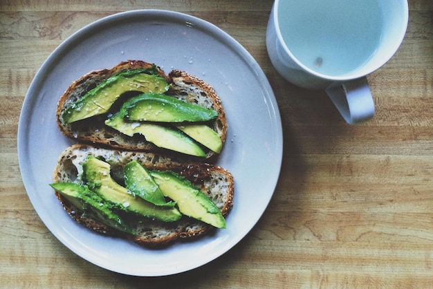 Hochwinkelansicht von geröstetem Brot mit Avocados auf dem Teller auf dem Tisch