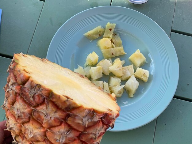 Foto hochwinkelansicht von geschnittener ananas auf einem teller auf dem tisch