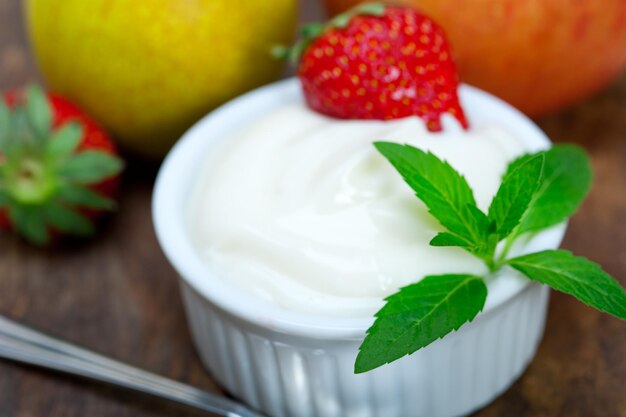 Hochwinkelansicht von Joghurt mit Erdbeeren und Blättern auf dem Tisch