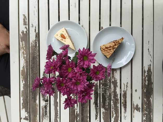 Foto hochwinkelansicht von karottenkuchen in tellern von blumen auf dem tisch