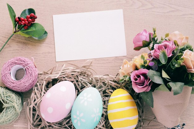 Foto hochwinkelansicht von leerem papier mit mehrfarbigen eiern und blumen auf dem tisch