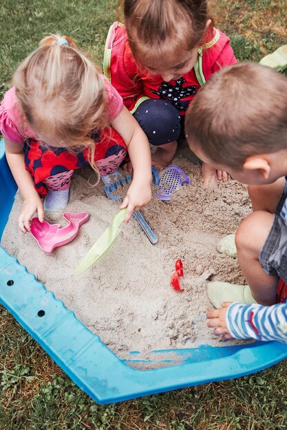 Foto hochwinkelansicht von mädchen, die auf dem gras sitzen und mit sand spielen